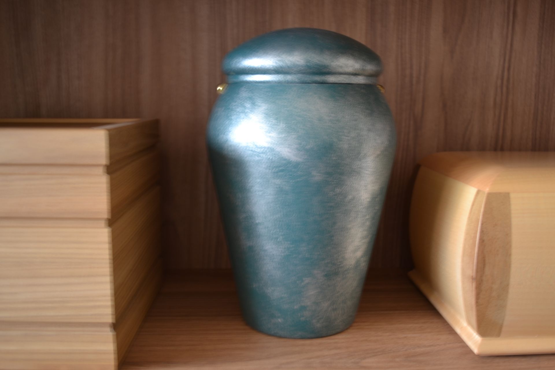 Urna blu appoggiata su uno scaffale di legno