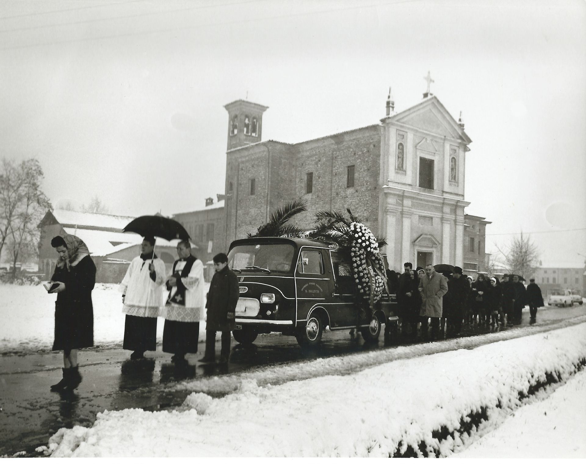 Una foto in bianco e nero di un corteo funebre davanti a una chiesa