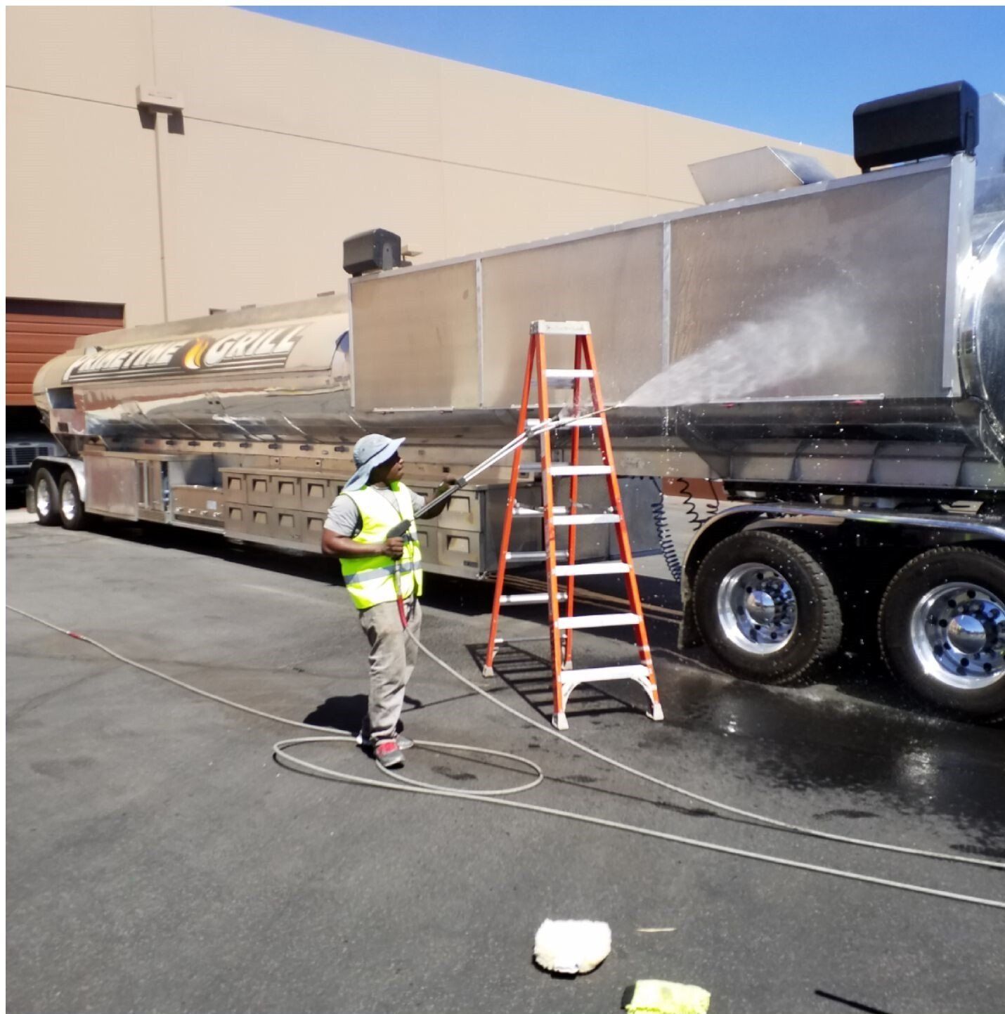 A man is washing a truck with a ladder in front of it