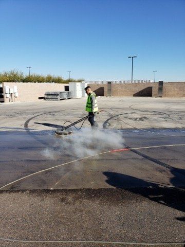 A man in a green vest is cleaning a parking lot