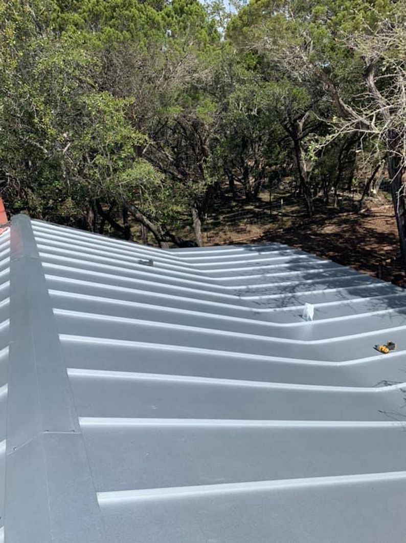 Metal roof with gray ridges, trees in background.