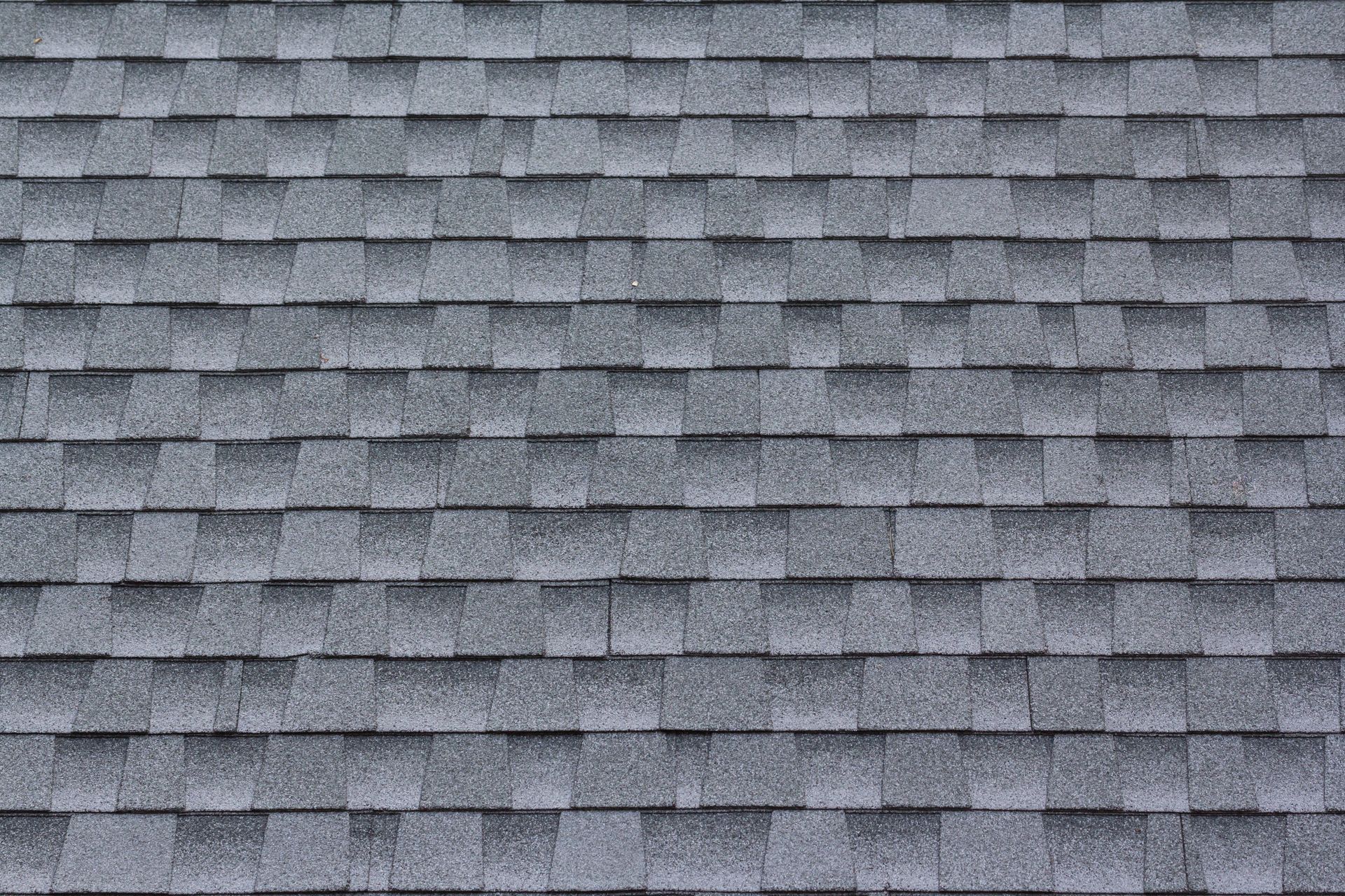 Gray asphalt shingle roof, textured surface, overlapping rows, neutral color.