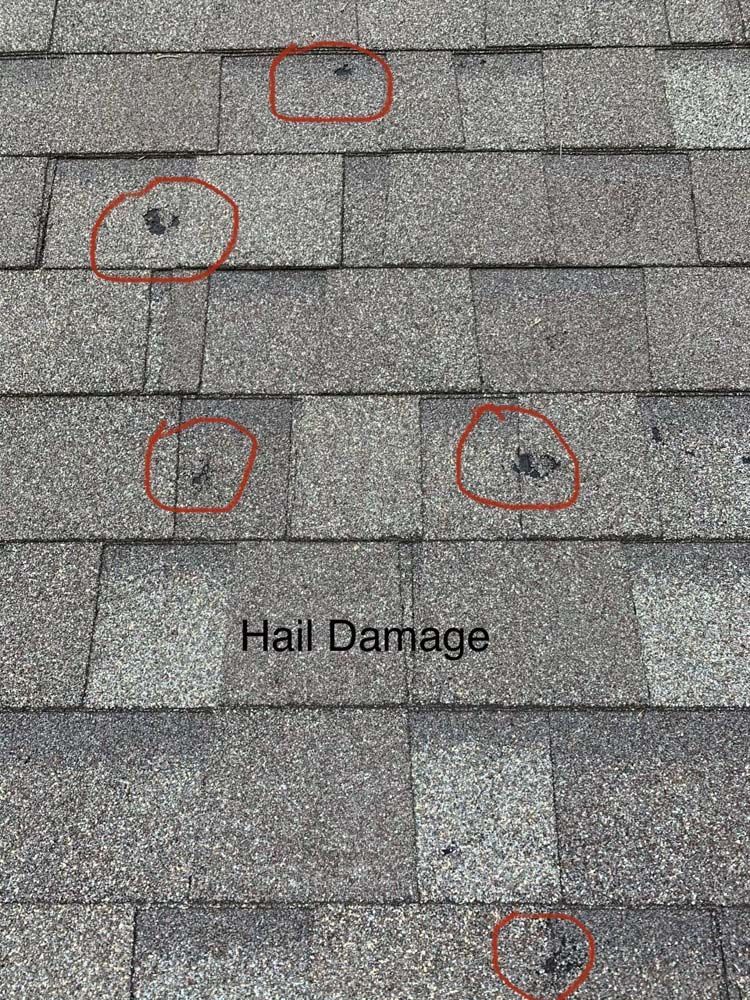 Gray shingle roof with several areas of visible hail damage marked with red circles.