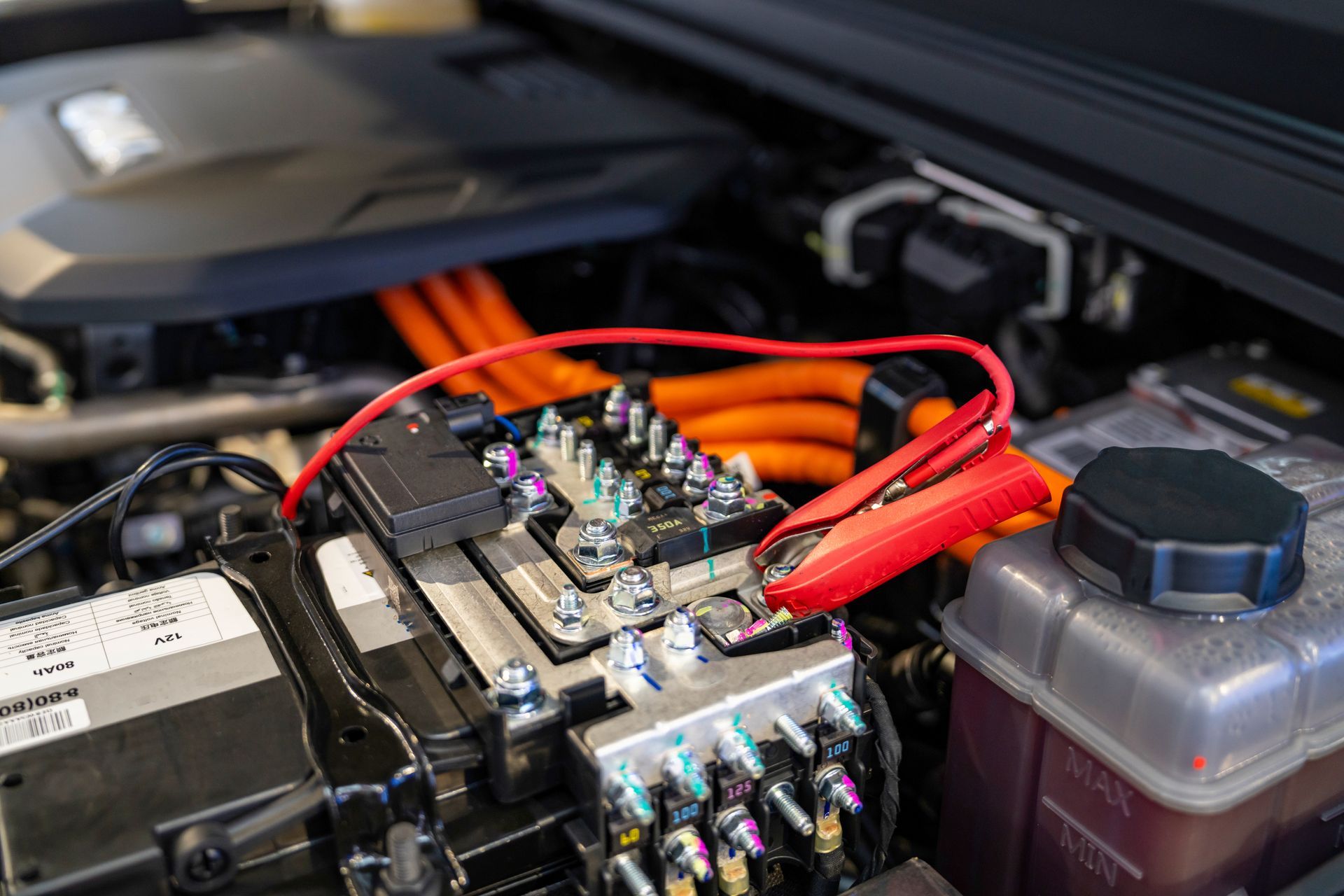Close-up of a car engine with red jumper cables attached to the battery.