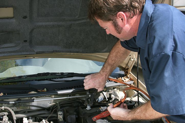 Close up of man hand charging a car battery using electricity through jumper cables.