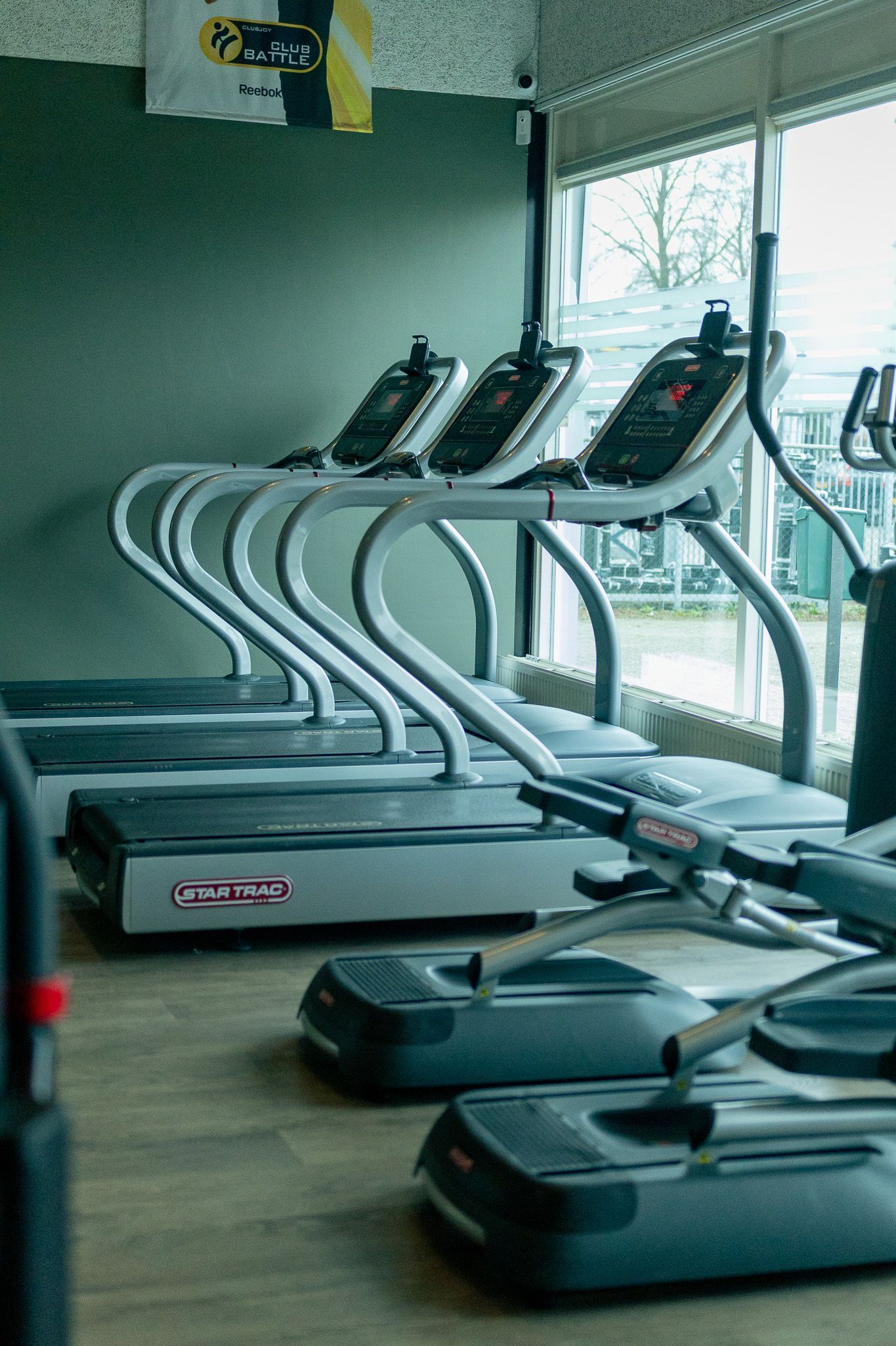 een zwart-witfoto van een sportschool met loopbanden en hometrainers.