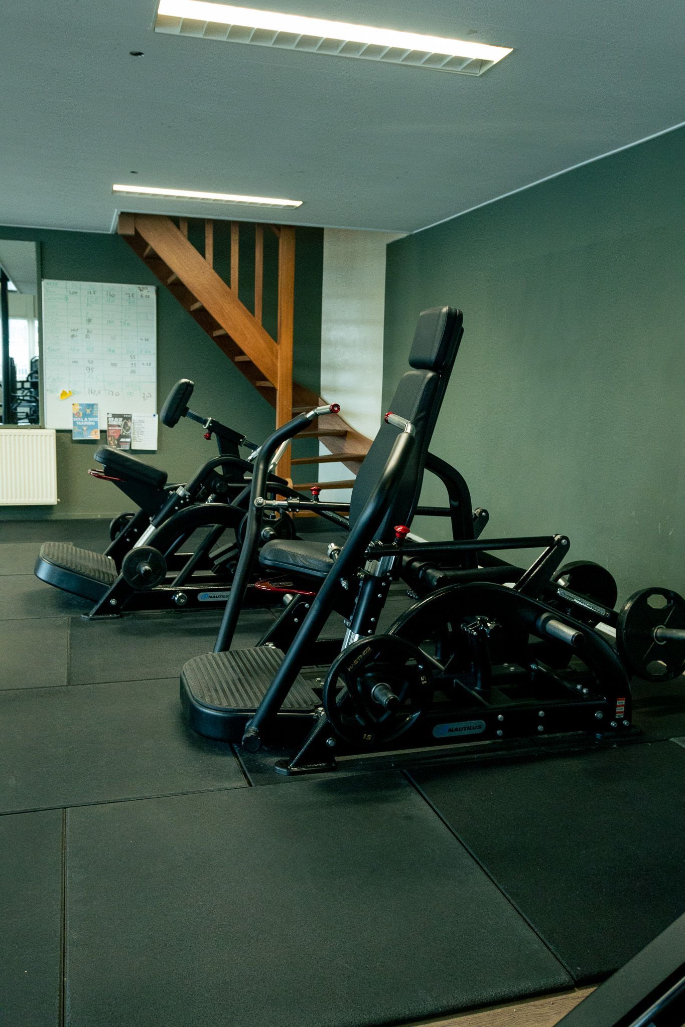 een zwart-witfoto van een sportschool met loopbanden en hometrainers.