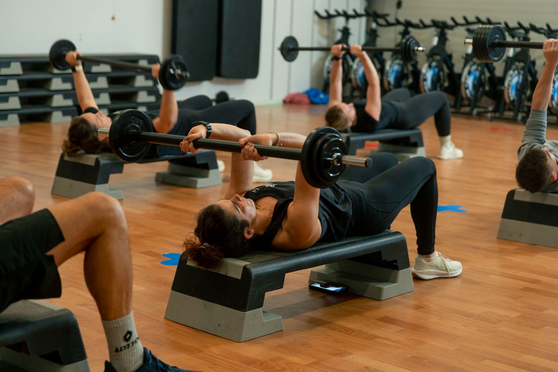 een vrouw tilt halters op voor een spiegel in een sportschool.