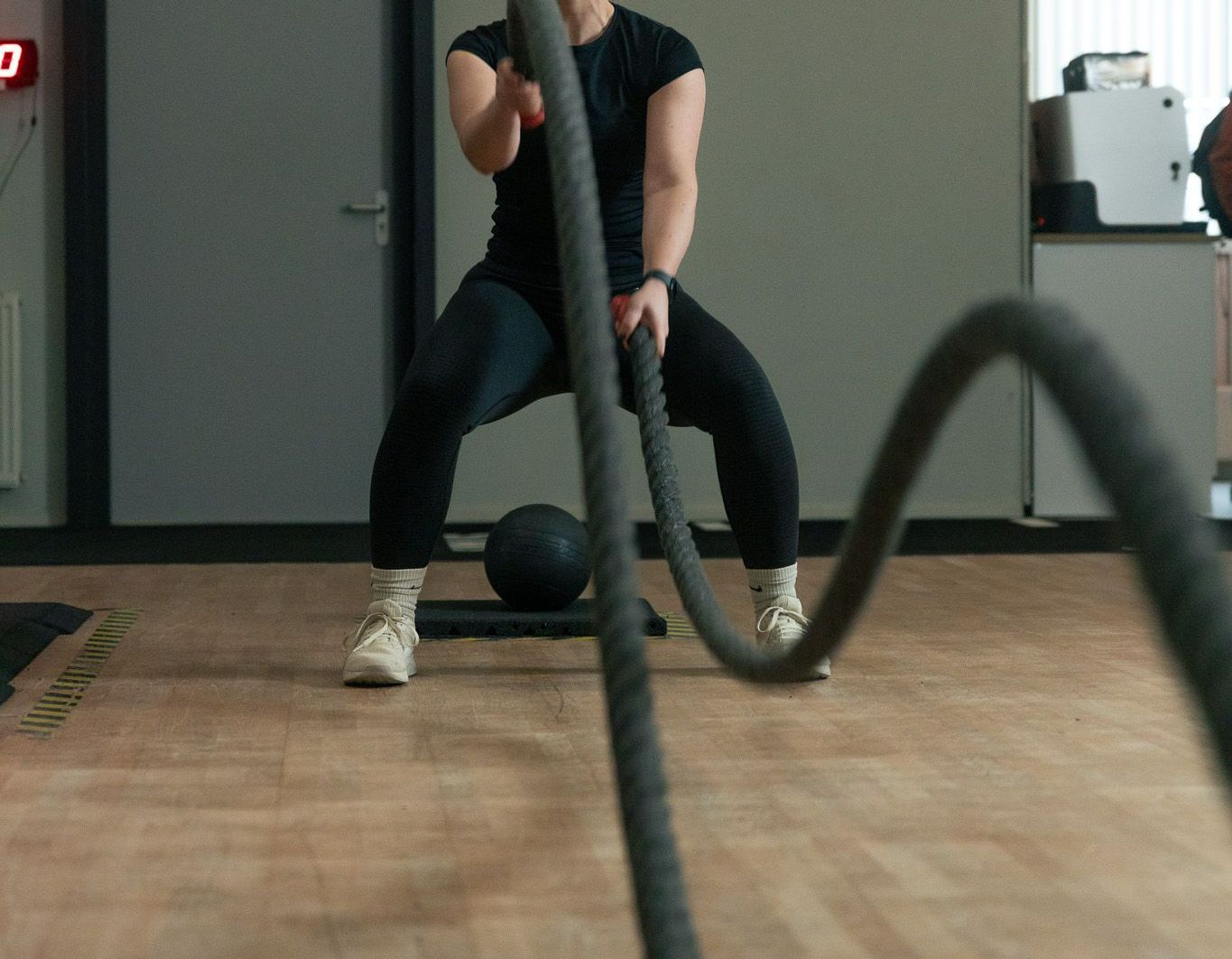 Een man hurkt met een touw in een sportschool