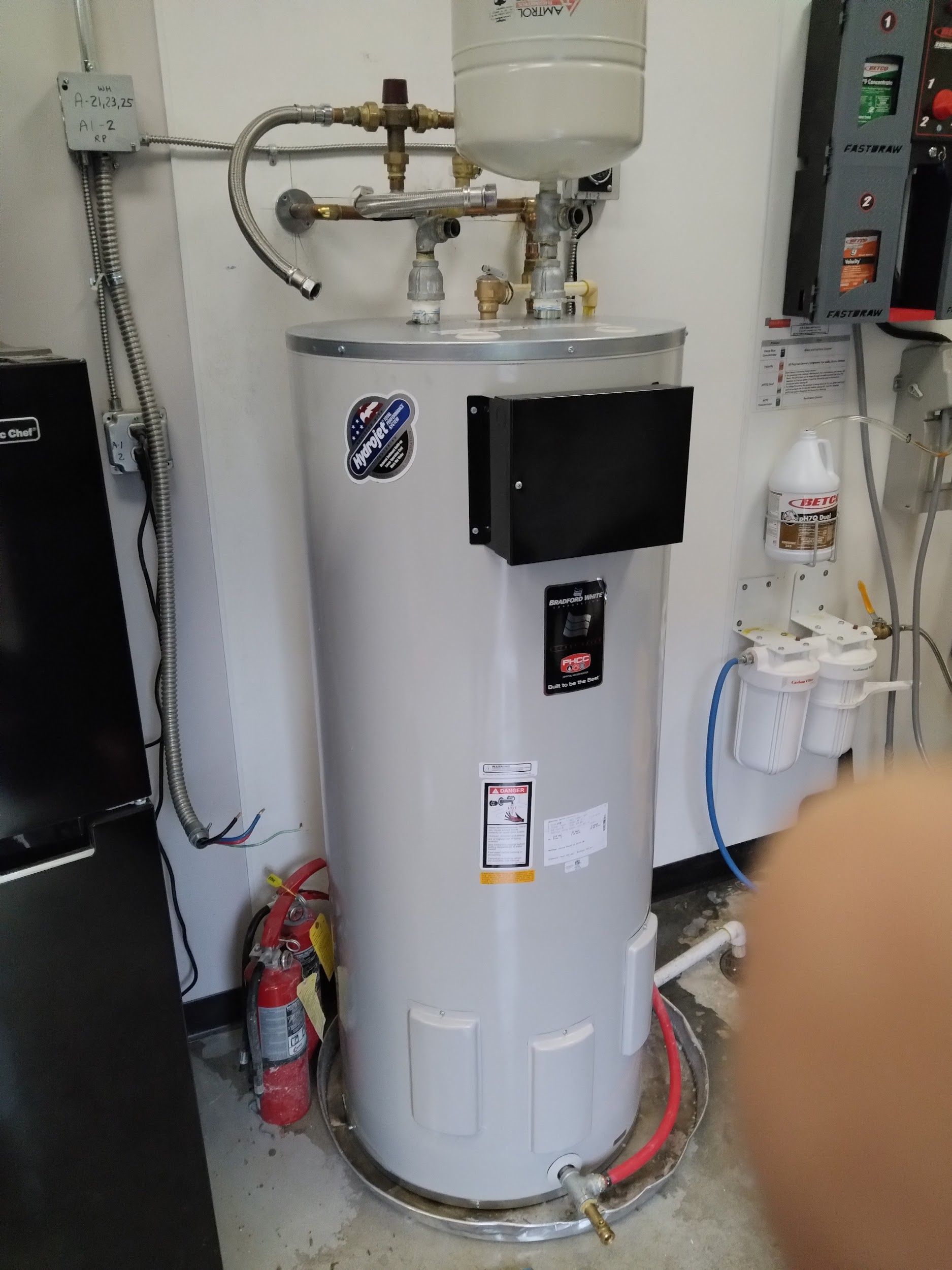 Narrow utility room with a washing machine, water heater, and doorway. Walls are light grey.