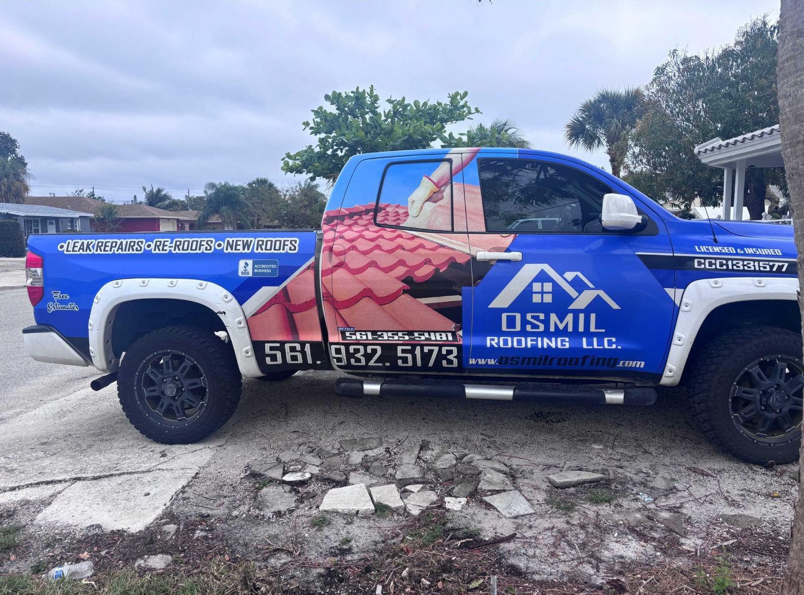 Blue pickup truck with a roofing advertisement wrap.