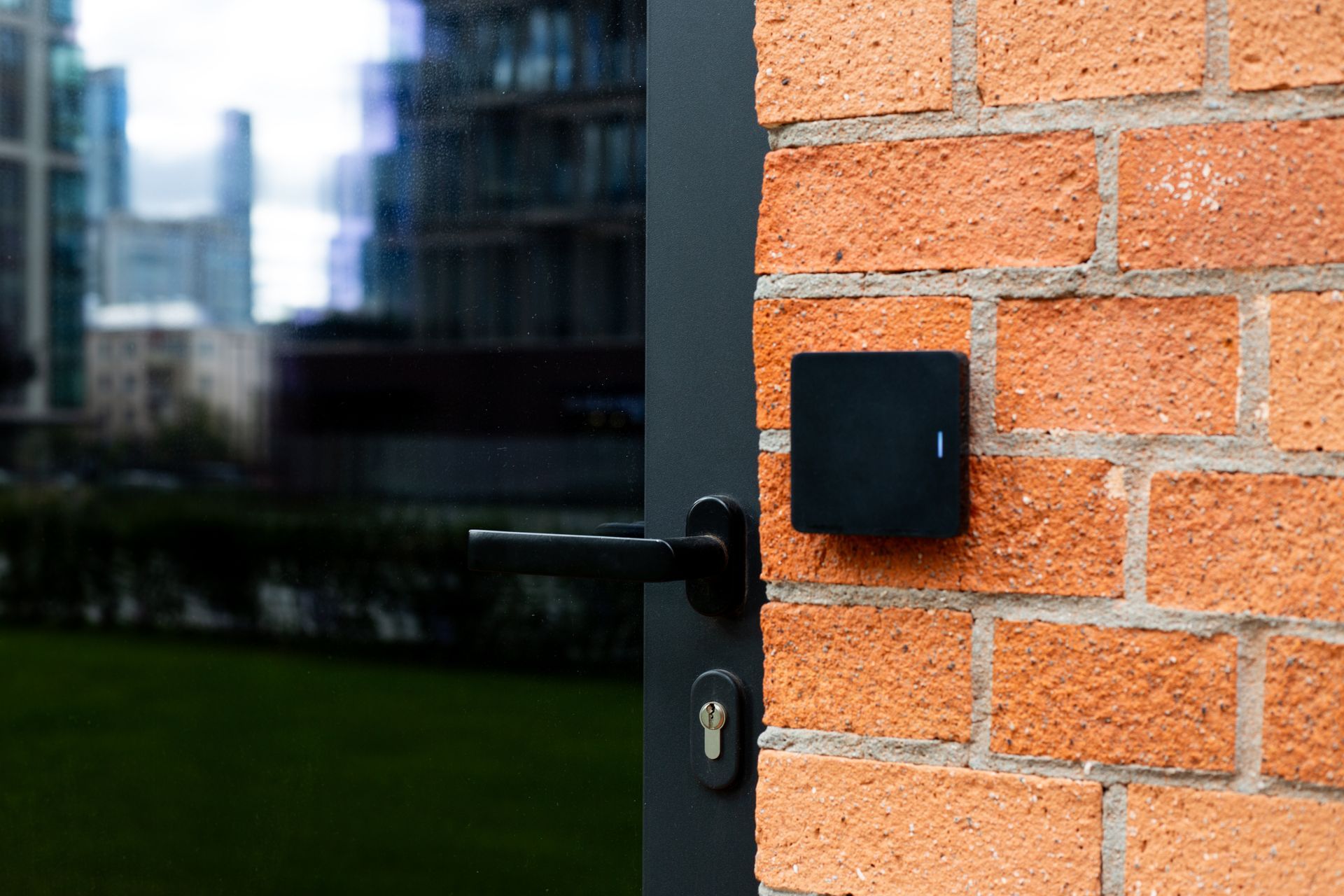 Exterior door with a black access control reader mounted on a brick wall