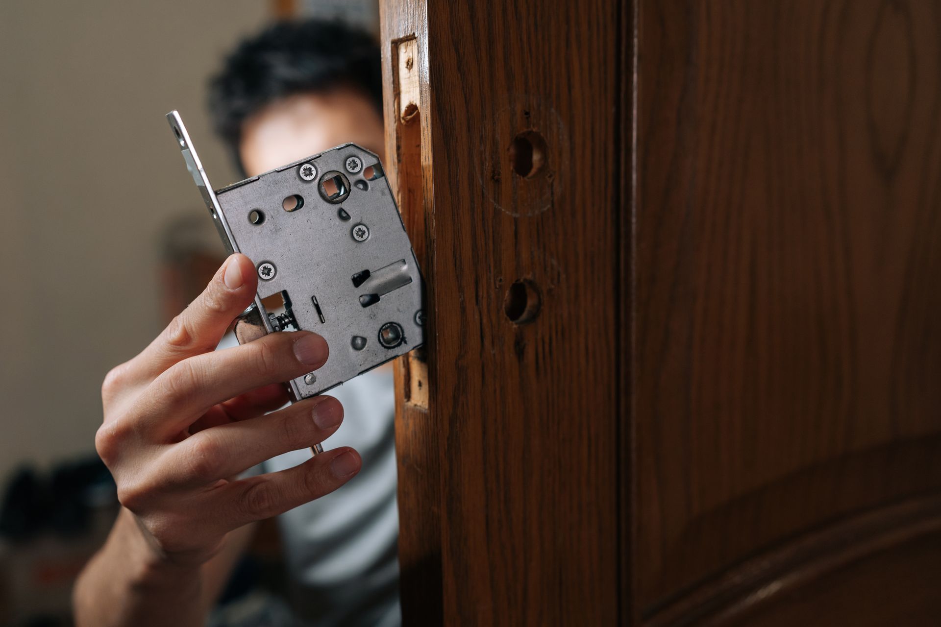 Security technician installing a mortise lock into a wooden door during a residential security system installation Security technician installing a mortise lock into a wooden door during a residential security system installation