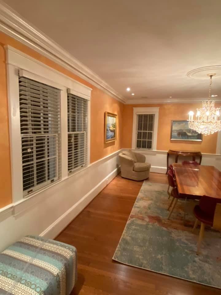 A living room with a wooden table and chairs and a chandelier.