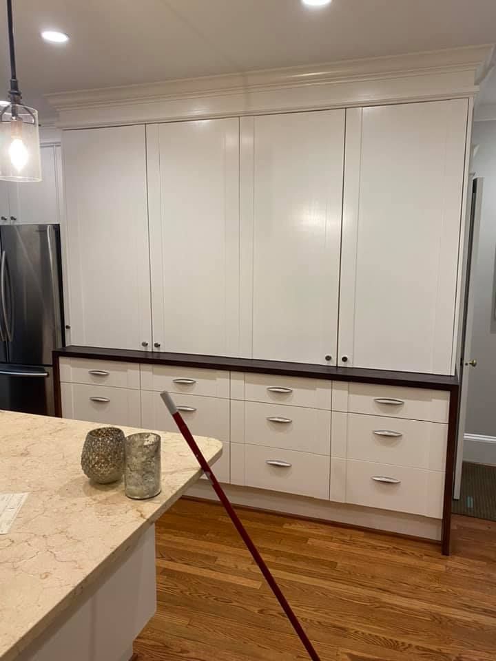 A kitchen with white cabinets and a mop on the counter.