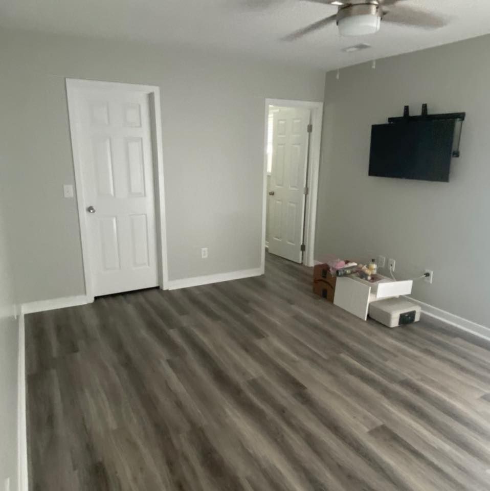 A living room with a ceiling fan and a flat screen tv on the wall.
