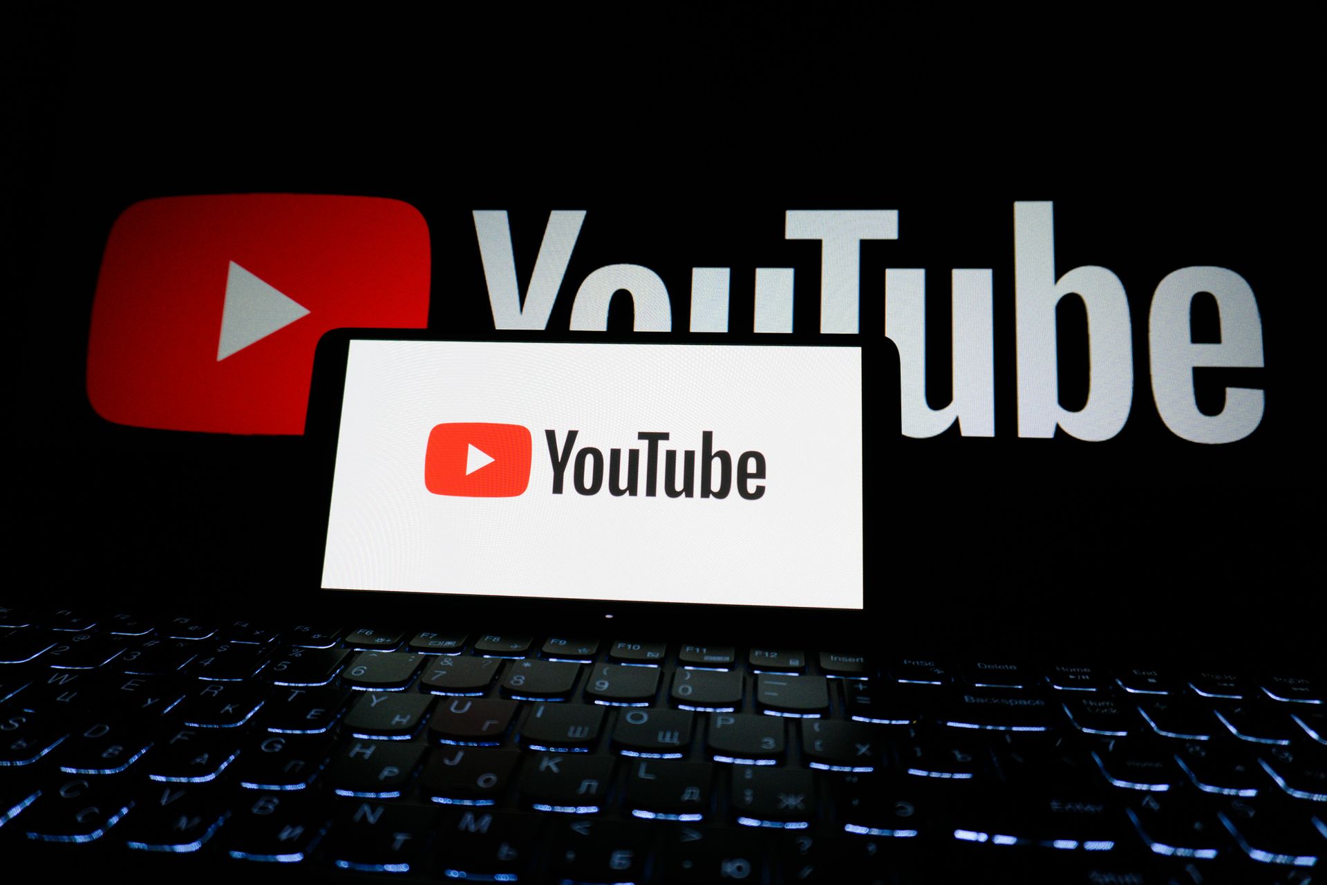 YouTube logos on a dark screen above a backlit keyboard