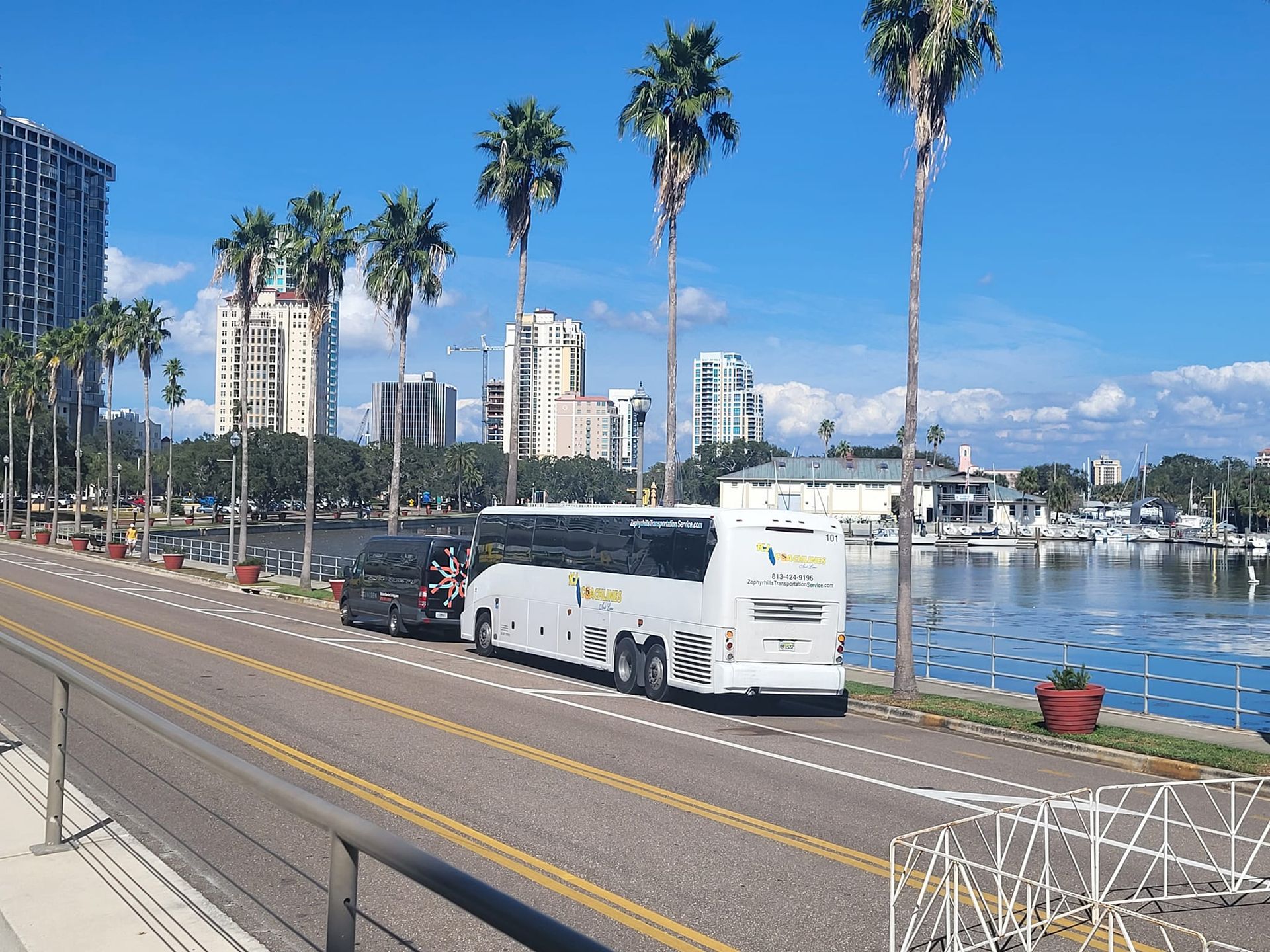 a white bus is parked on the side of the road next to a body of water