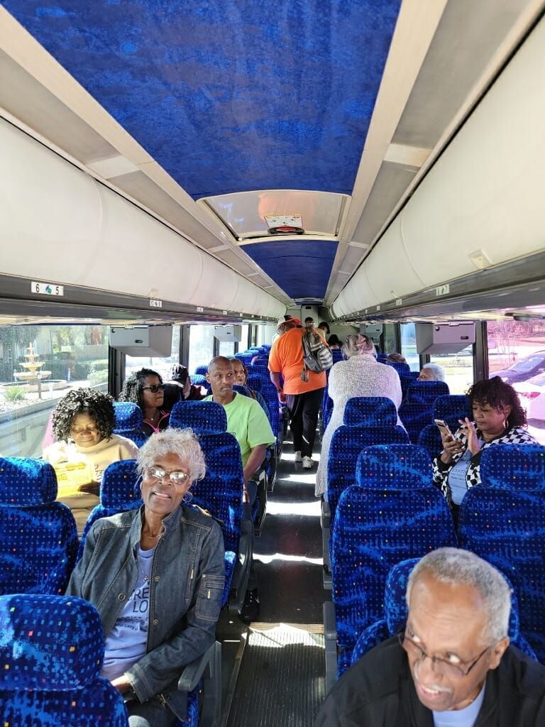 a group of people are sitting on a bus with blue seats