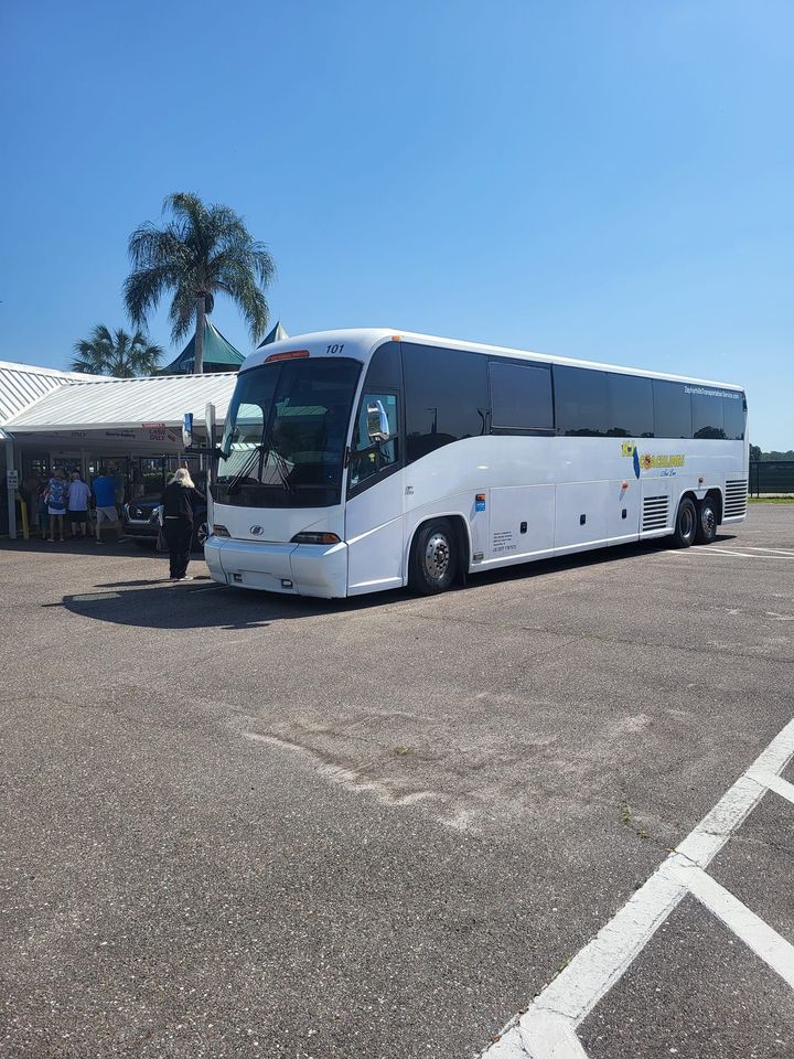 a large white bus is parked in a parking lot