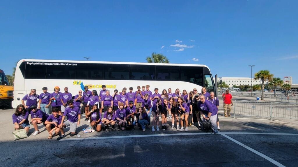 a large group of people are posing for a picture in front of a bus