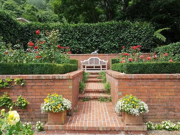 A brick walkway leading to a bench in a garden