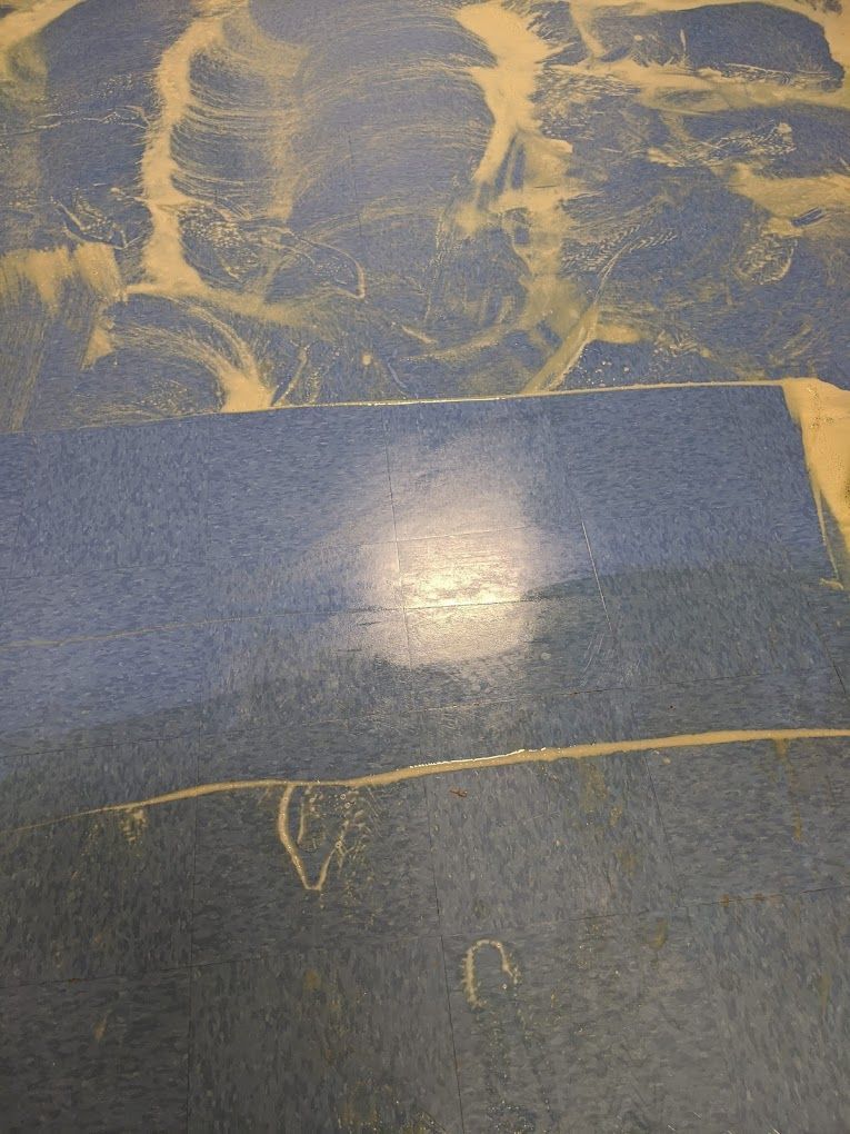 A blue tile floor with a few spots of stains on it.