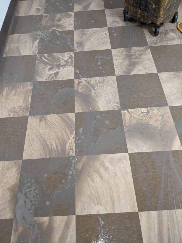 A checkered floor with a trash can in the background.