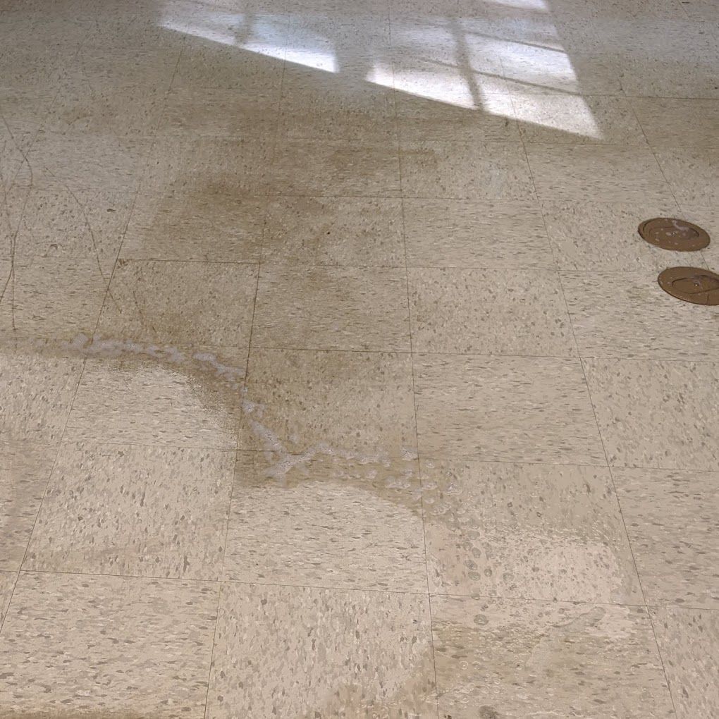 A close up of a tiled floor with a puddle of water on it.