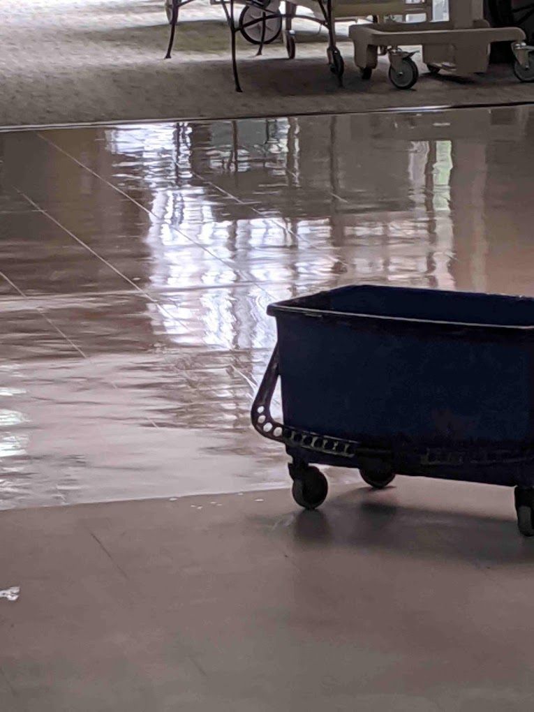A blue cart with wheels is sitting on a tiled floor.