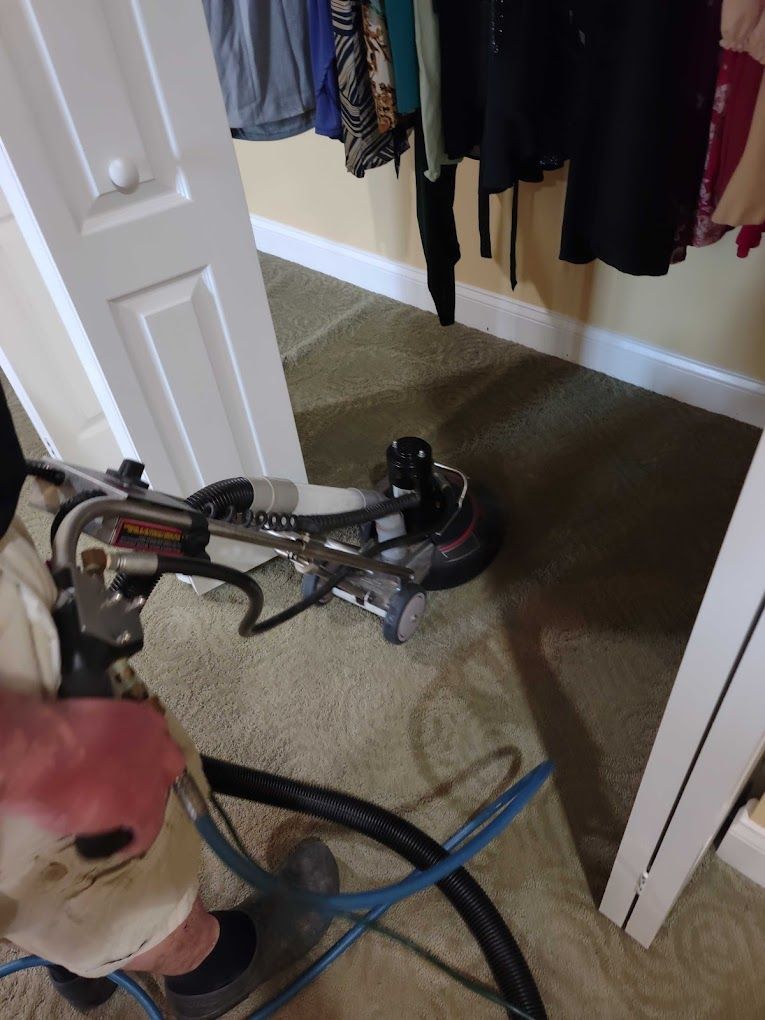 A person is using a vacuum cleaner to clean a carpet in a closet.