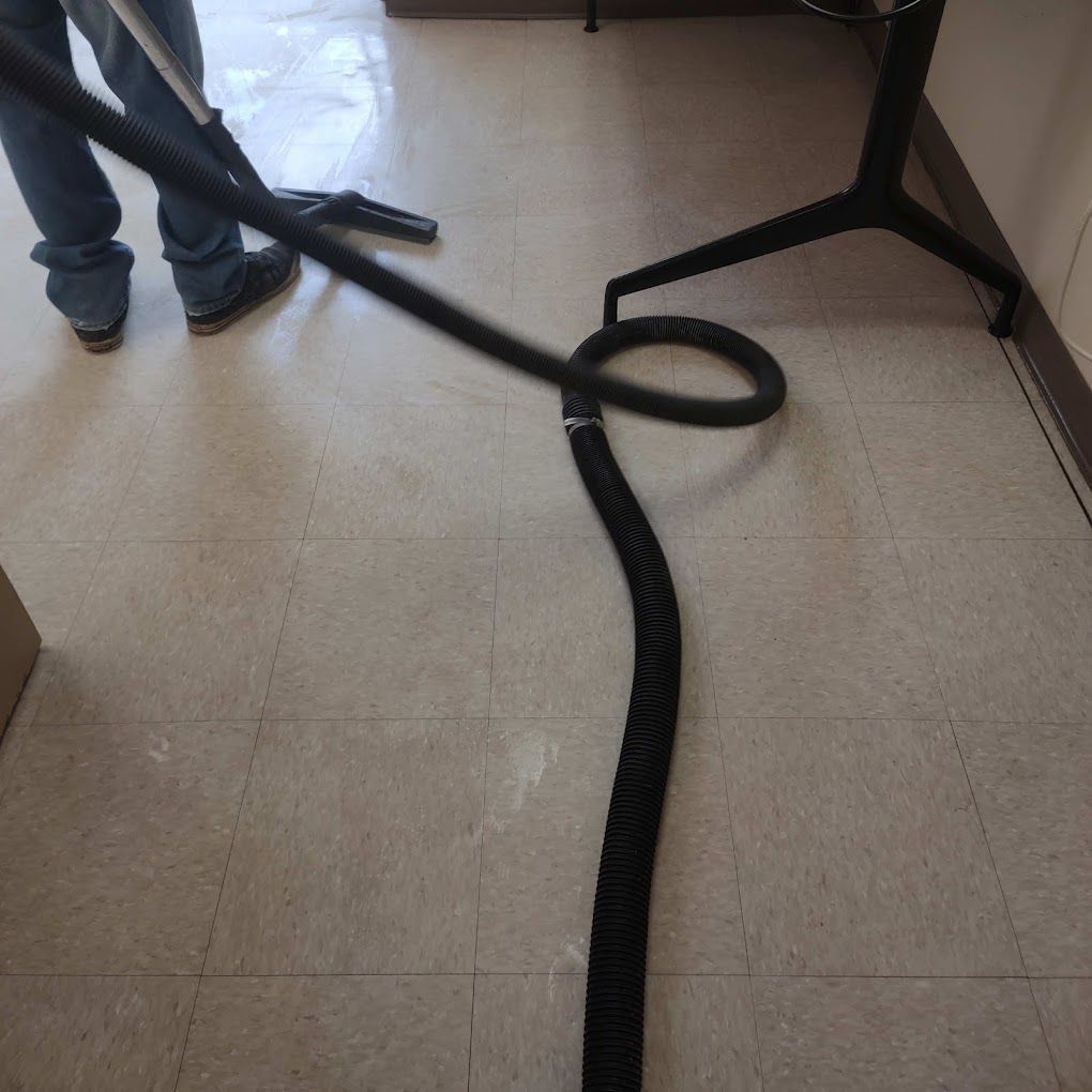 A person is using a vacuum cleaner on a tiled floor