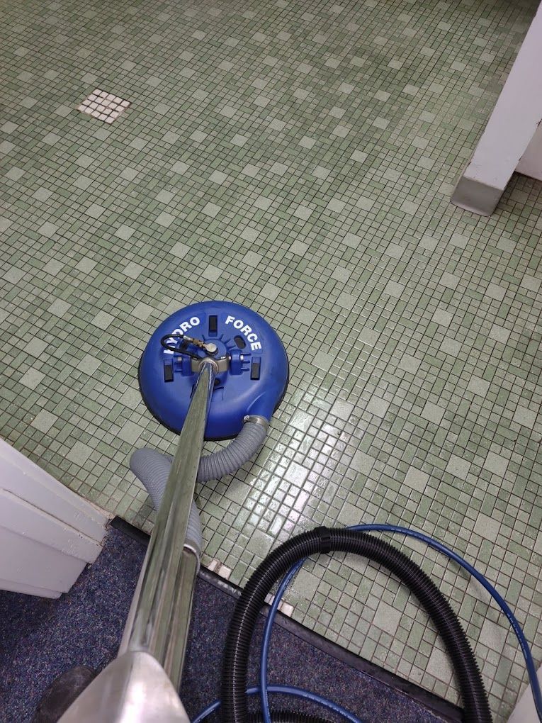 A vacuum cleaner is cleaning a tiled floor in a bathroom.