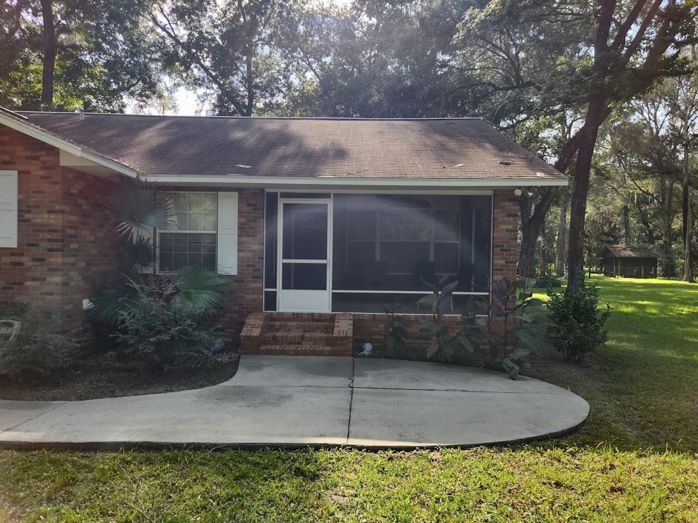 A brick house with a screened in porch and a concrete walkway