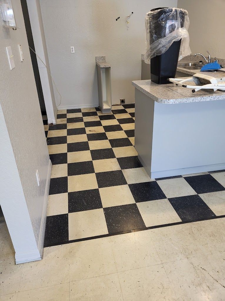 A kitchen with a black and white checkered floor and a trash can on the counter.