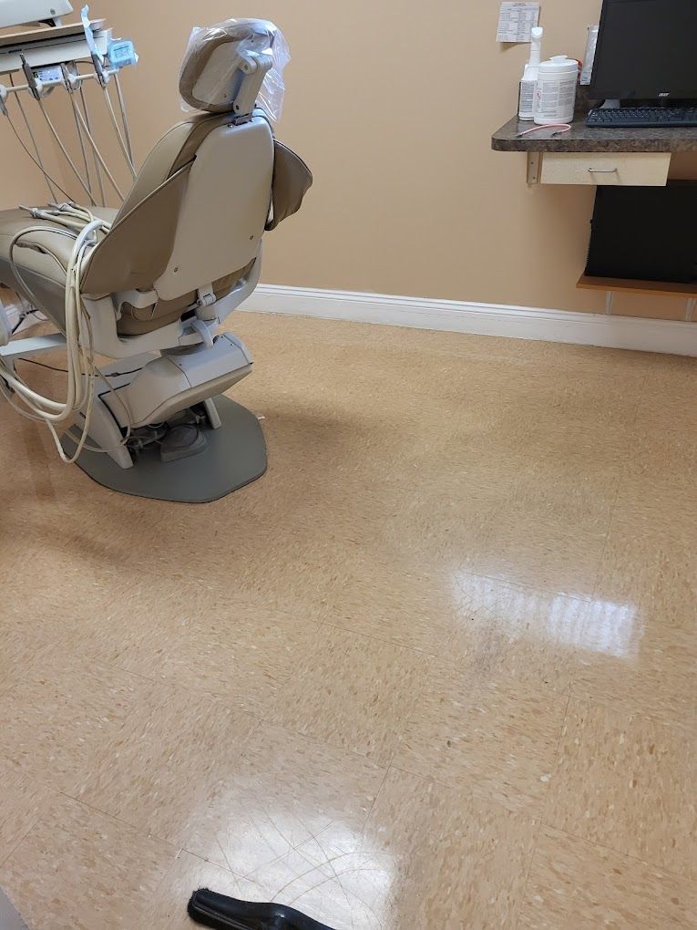 A dental chair is sitting in a dental office next to a computer.