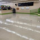 A large empty room with a white floor and a green railing.