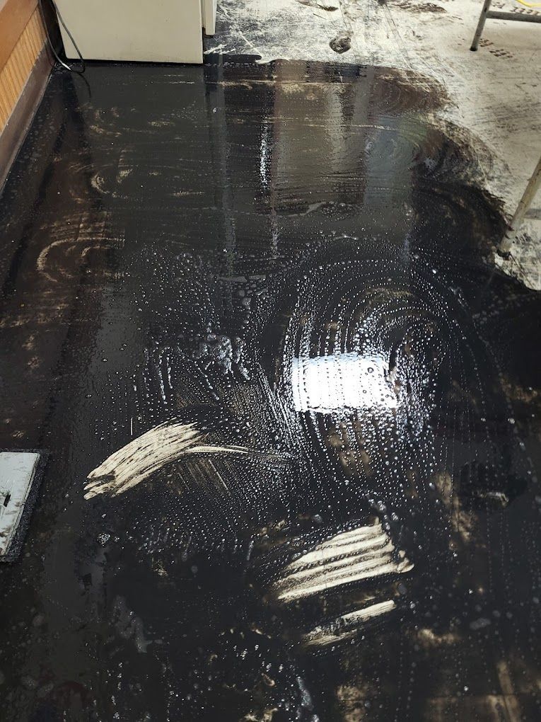 A black tile floor with a lot of water on it.