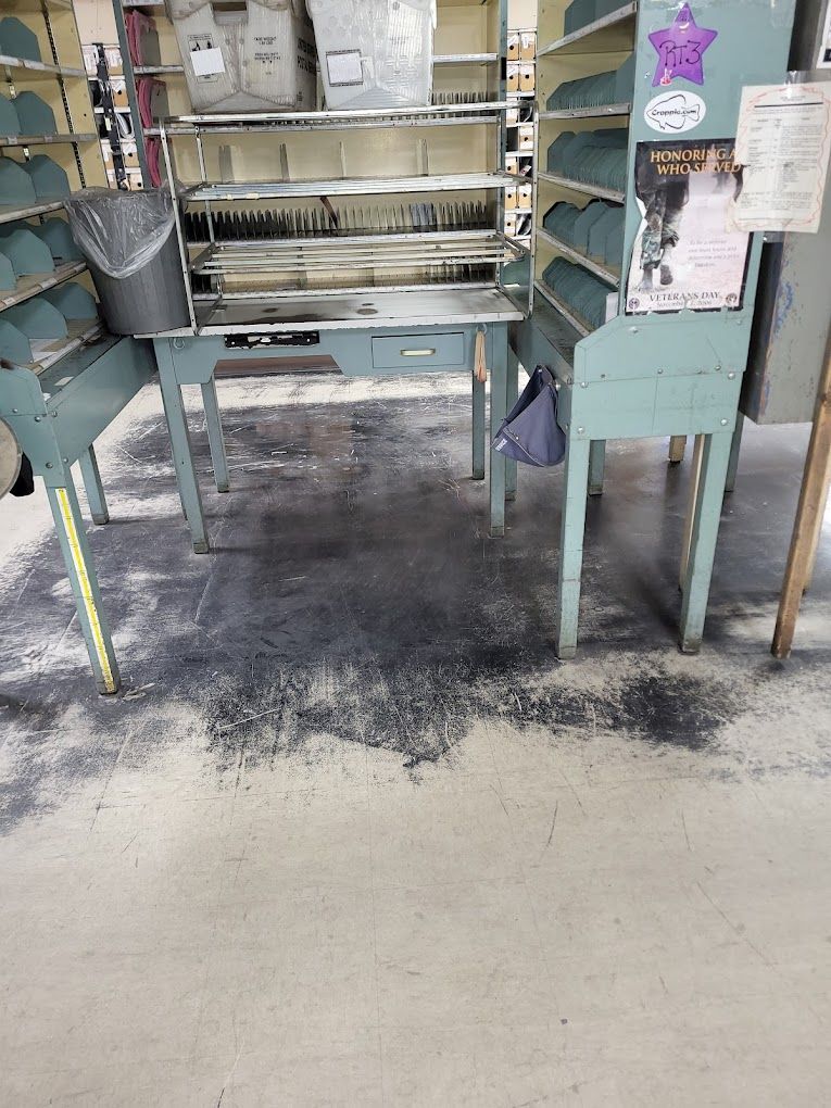 A dirty floor in a room with a table and shelves.