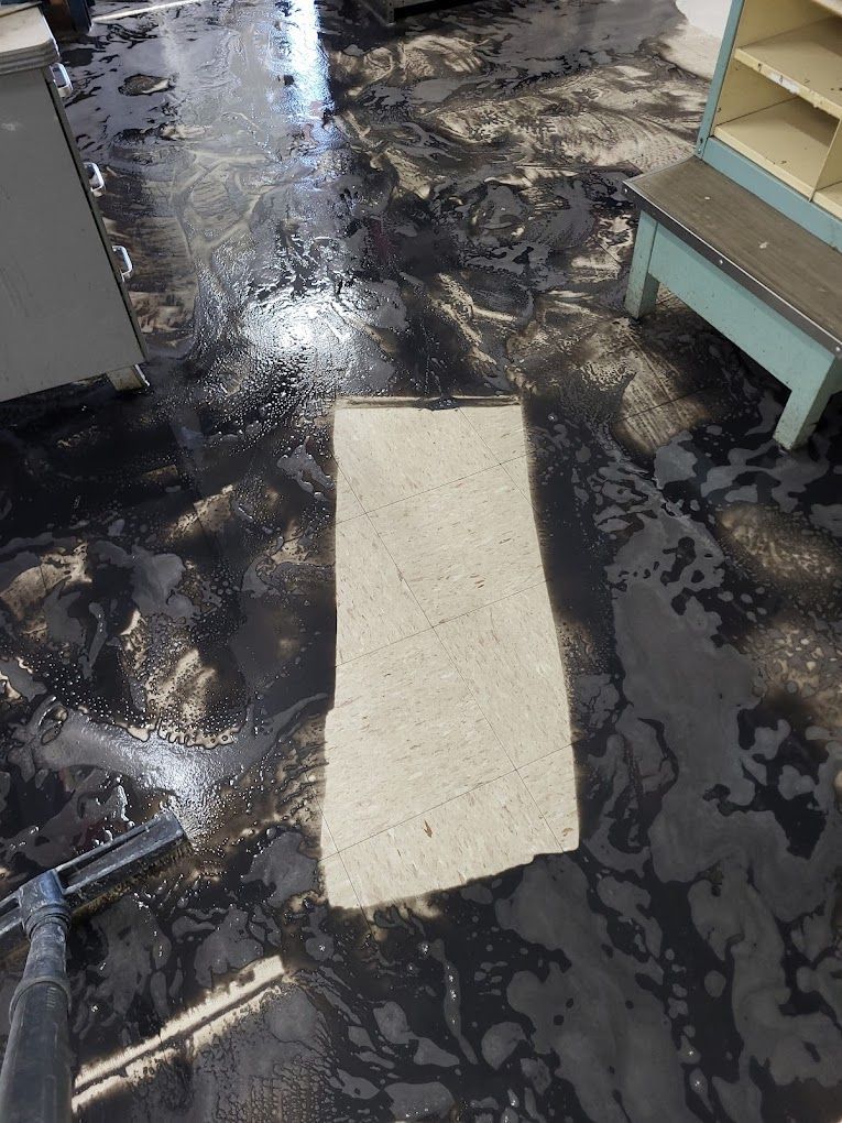 A person is cleaning a dirty floor with a vacuum cleaner.
