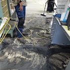 A man is cleaning a dirty floor with a vacuum cleaner.