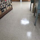 A shiny white floor in a room with shelves and a table.