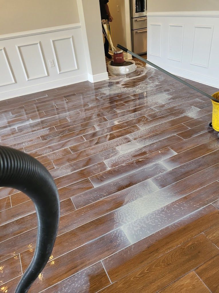 A vacuum cleaner is cleaning a wooden floor in a living room.