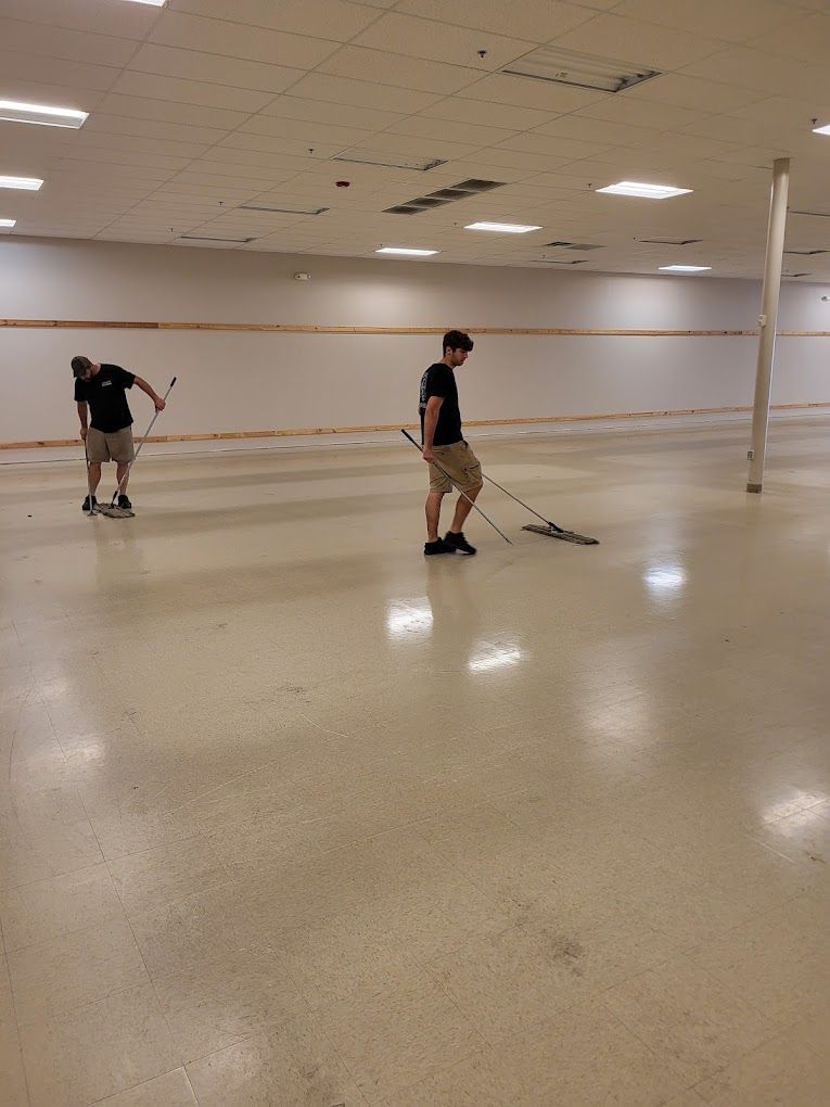 Two men are mopping the floor of an empty room