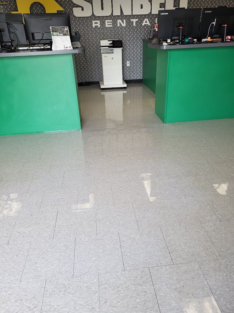A green counter in a store with a printer on the floor.