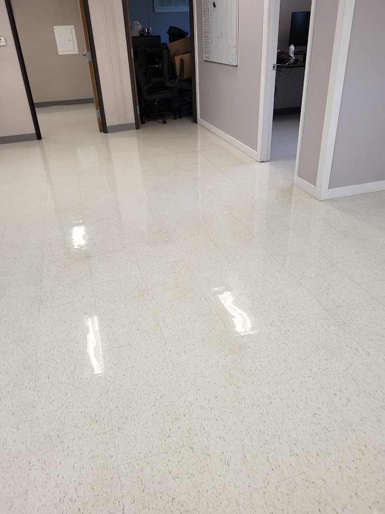 A room with a shiny white floor and a doorway leading to another room.