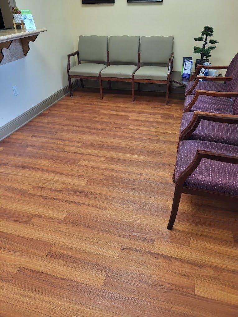 A waiting room with wooden floors and purple chairs.