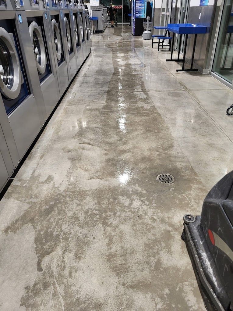 A laundromat with a lot of washing machines and a vacuum cleaner on the floor.