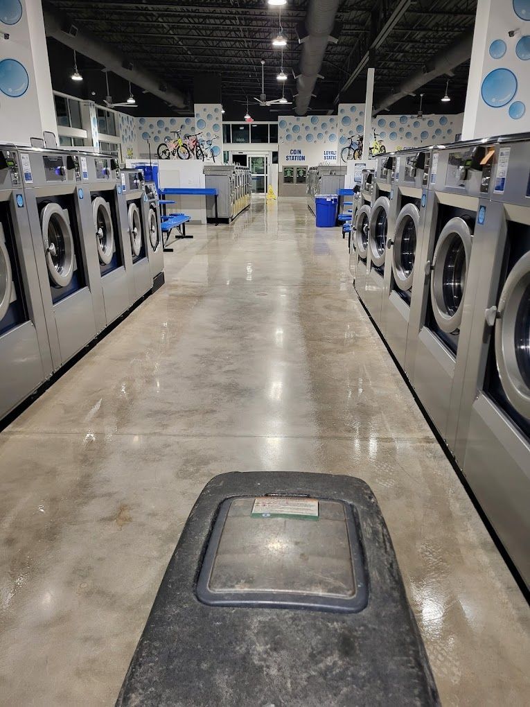 A row of washing machines in a laundromat with a trash can in the middle.