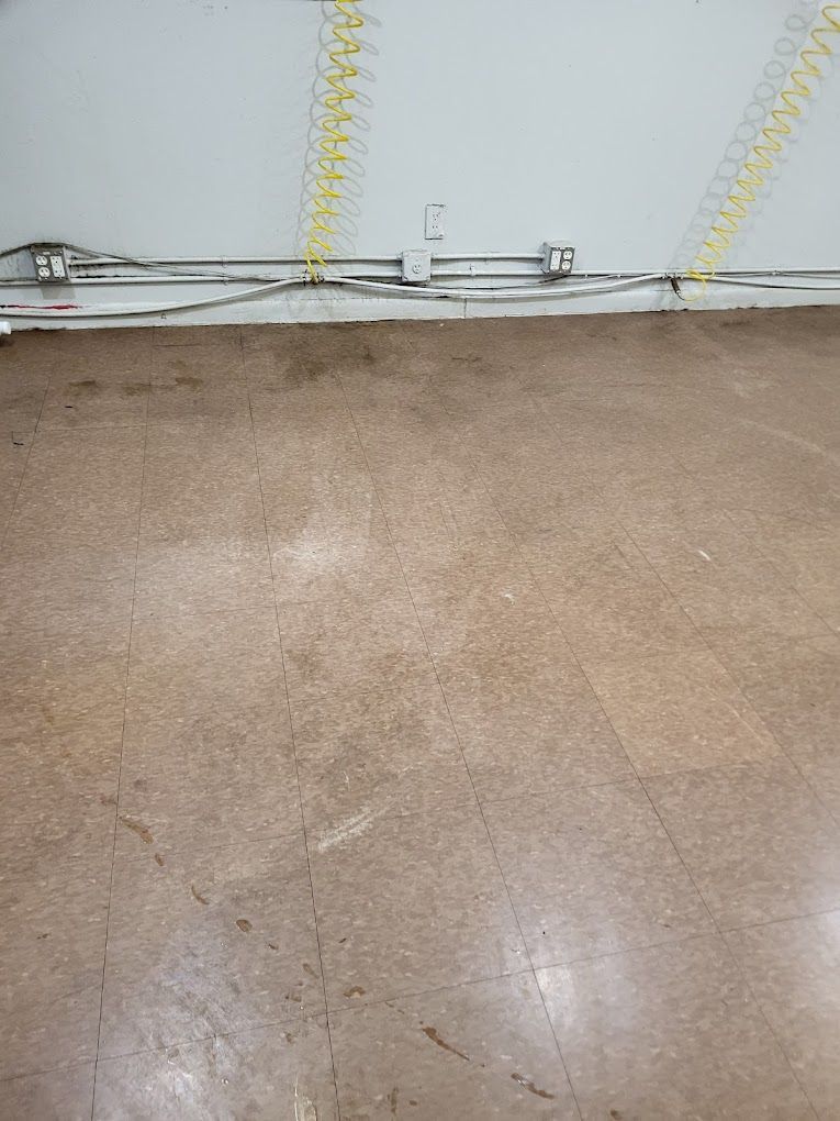 A dirty floor with a lot of wires hanging from the ceiling.